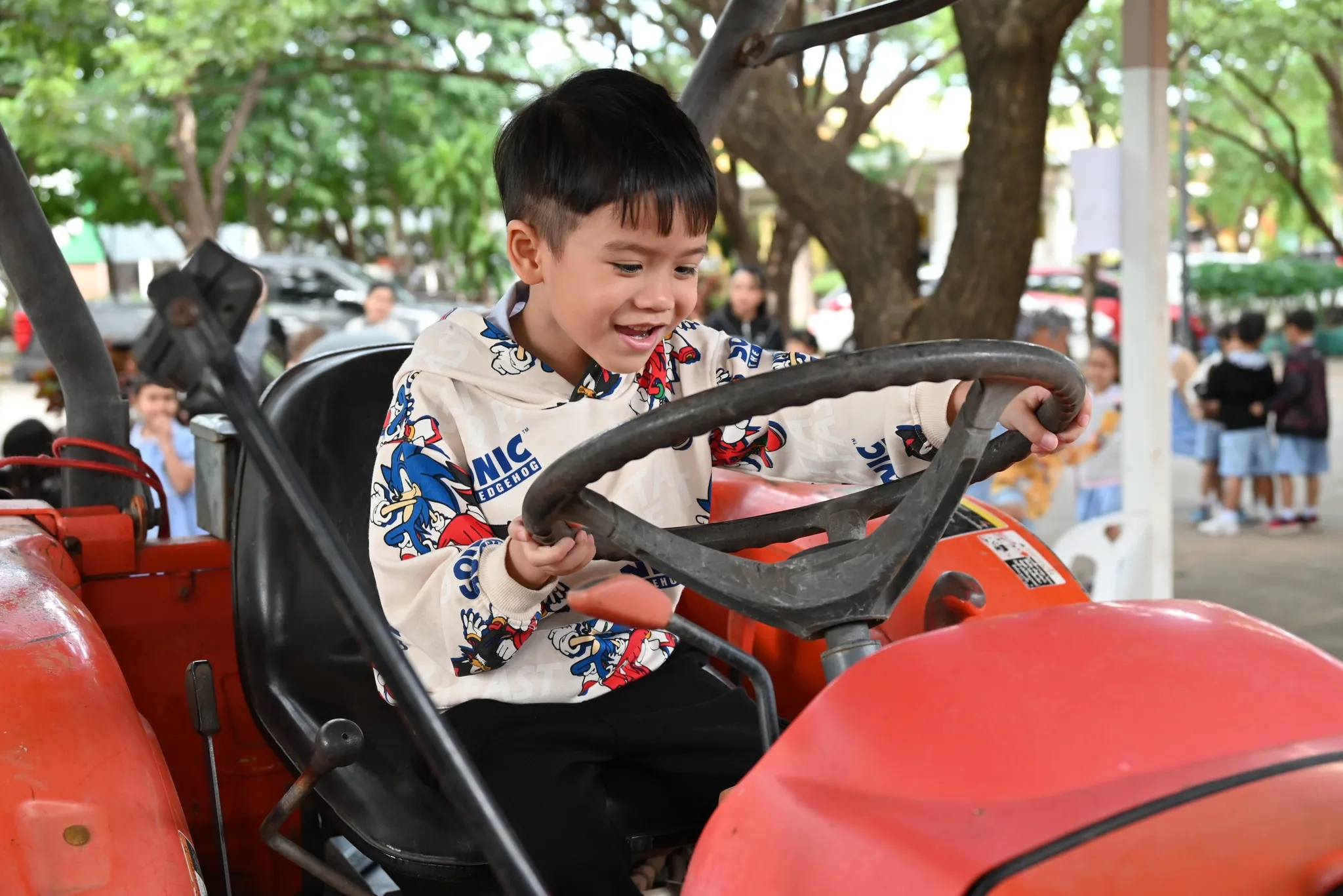 เด็กสนุกสนานกับการเล่นสมมติบนรถแทรกเตอร์สีแดง