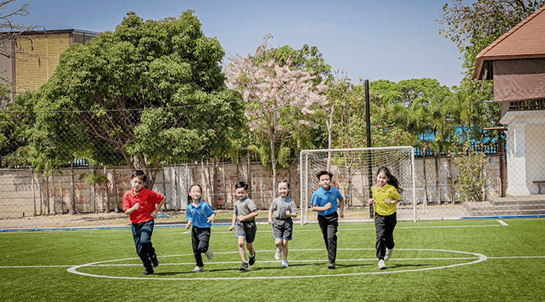 นักเรียนเล่นฟุตบอลบนสนามกลางแจ้ง